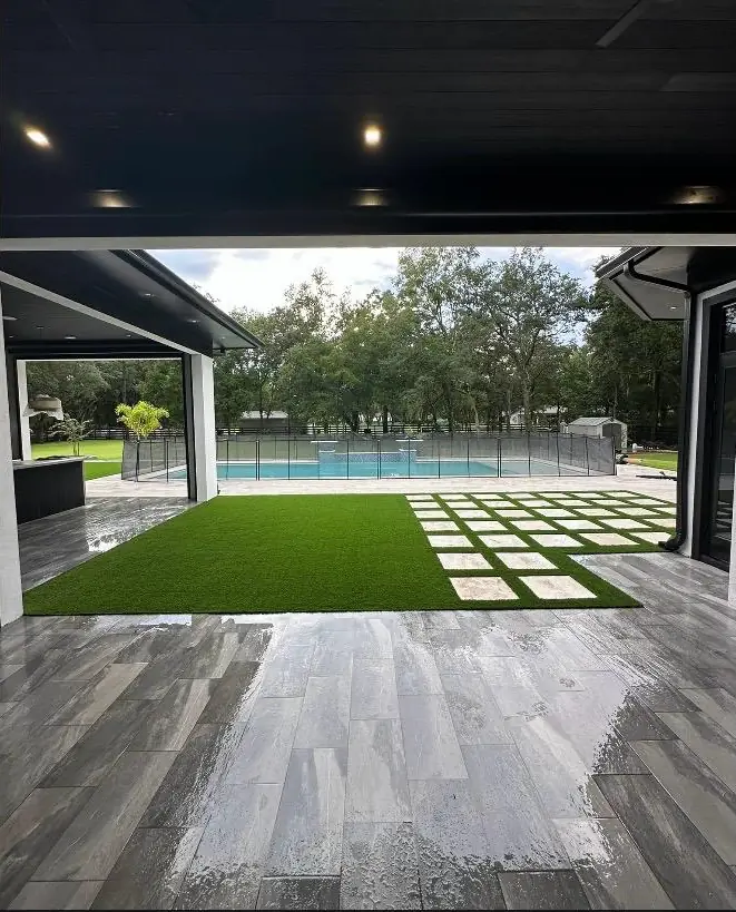 Área de piscina moderna con grama sintética y losas en diseño tablero