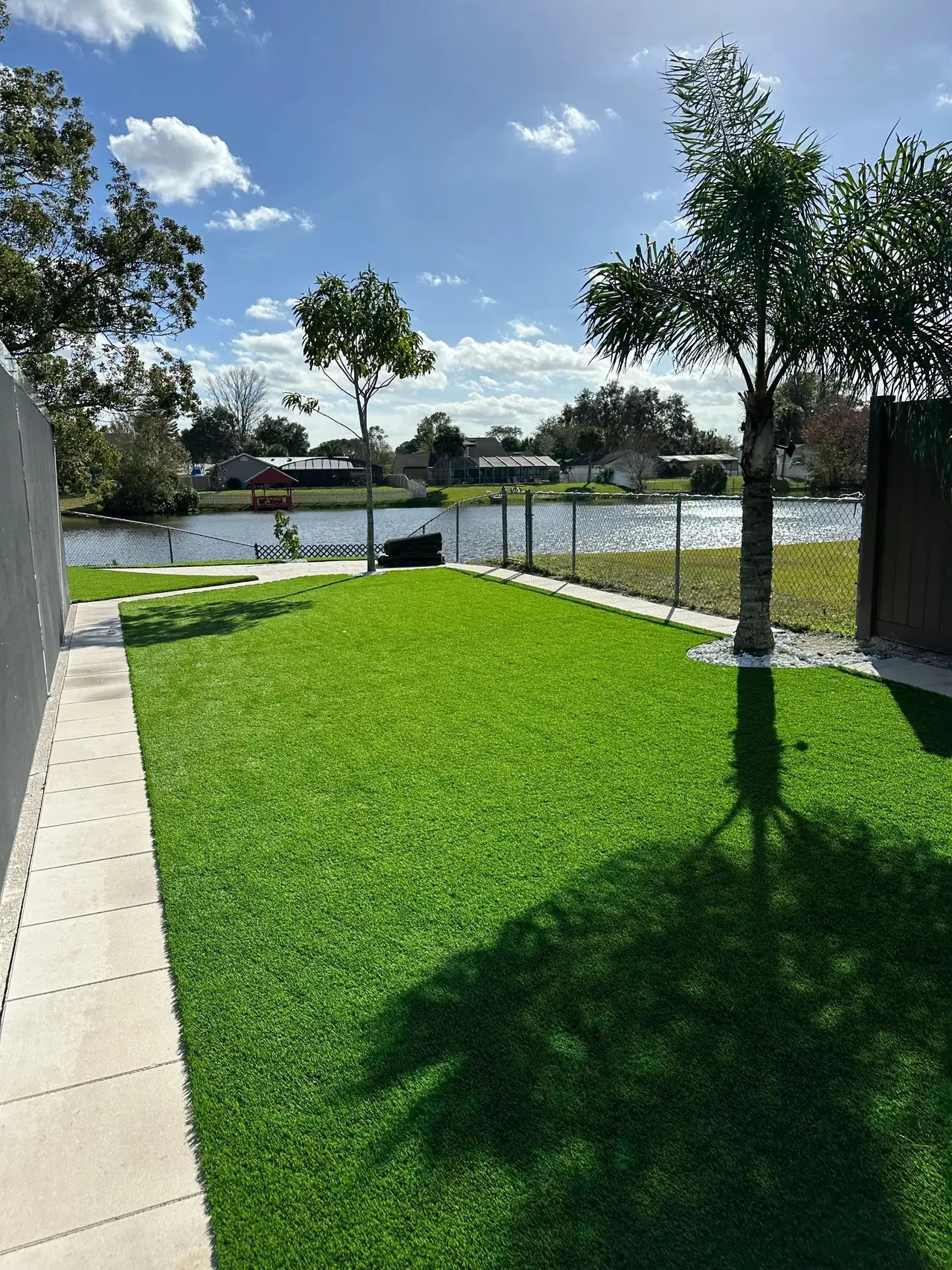 Jardín de grama sintética con palmeras y vista a un lago